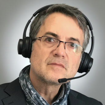 Mann mit Brille und Headset, trägt einen Schal und einen Anzug.