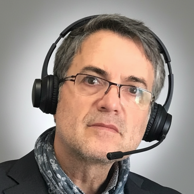 Mann mit Brille und Headset, trägt einen Schal und einen Anzug.