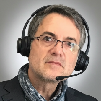 Mann mit Brille und Headset, trägt einen Schal und einen Anzug.